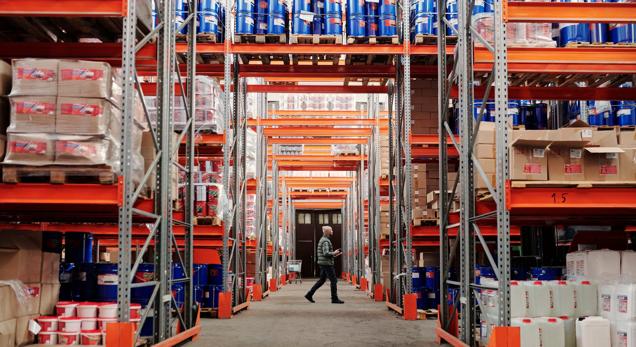 A long warehouse aisle of racked pallets receding into the distance